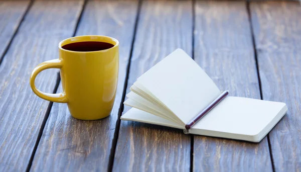 Šálek kávy a zápisník s tužkou — Stock fotografie