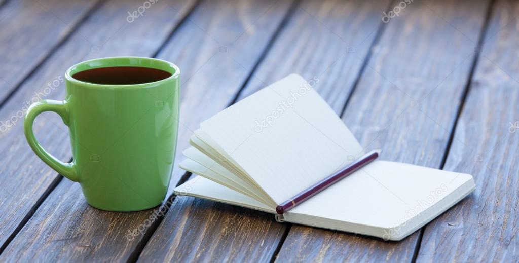 Cup of coffee and notebook with pencil