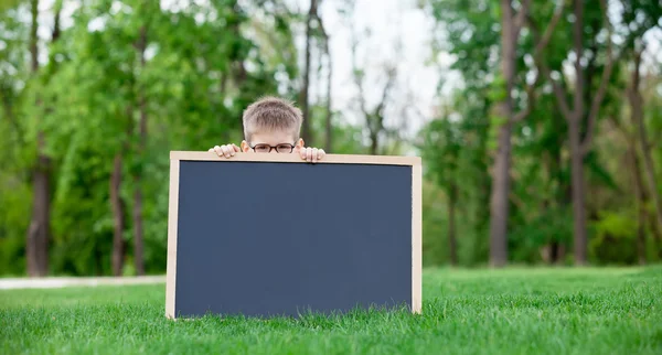 Jeune garçon avec un tableau noir — Photo