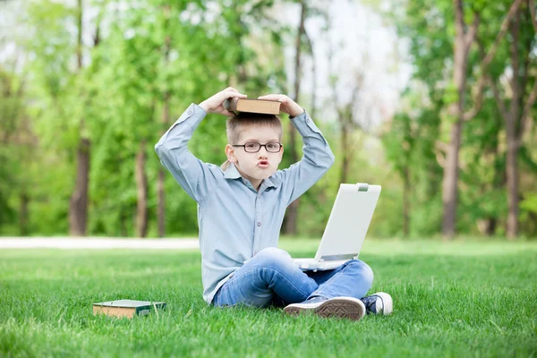 Молодий здивований хлопчик з книжками і ноутбуком — стокове фото