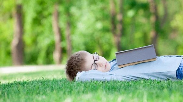 Young boy with a book slipping — Stock Photo, Image