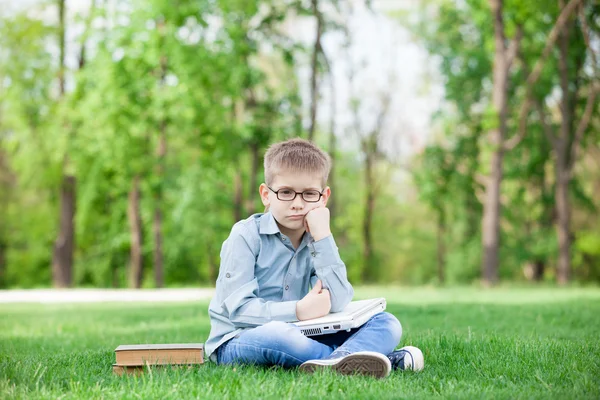 Kleiner trauriger Junge mit Büchern und Laptop — Stockfoto