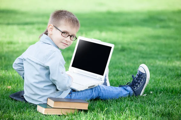 Niño con un ordenador portátil y libros — Foto de Stock