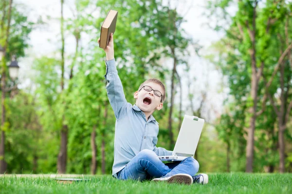 Jeune garçon surpris avec un livre et un ordinateur portable — Photo