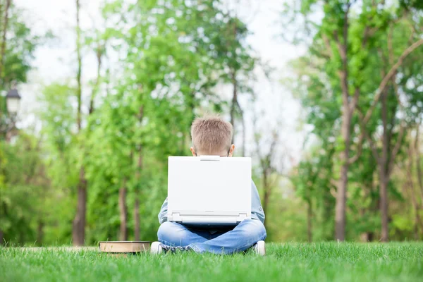 Niño con un ordenador portátil y libros — Foto de Stock