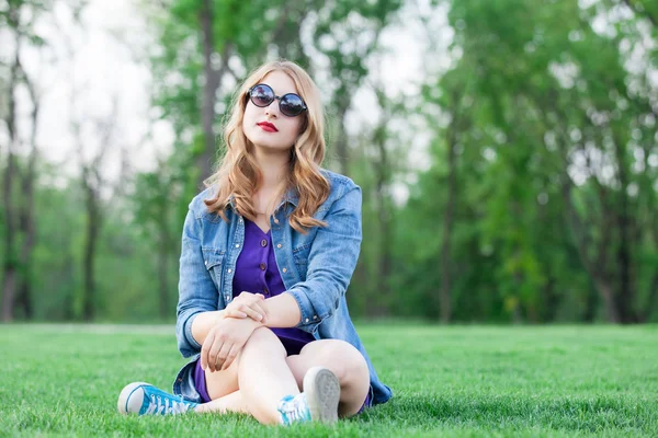 Mulher loira sentada na grama verde — Fotografia de Stock
