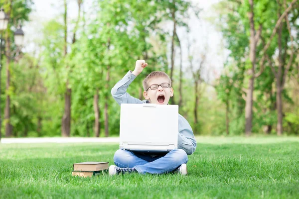 Niño con un ordenador portátil y libros — Foto de Stock