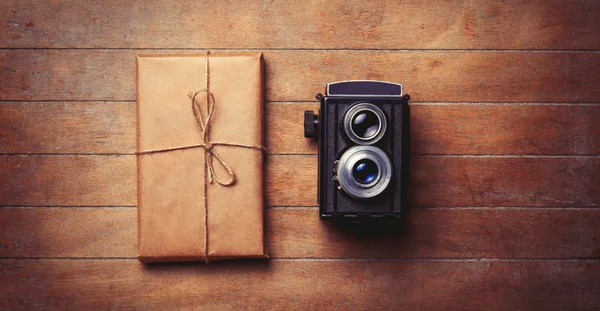 Fotoaparát a balíček na dřevěný stůl. — Stock fotografie