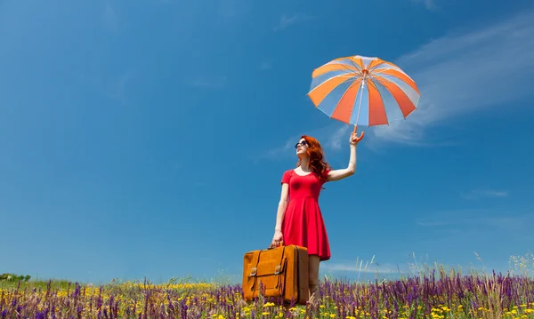 Mulher de vestido vermelho com guarda-chuva e mala — Fotografia de Stock