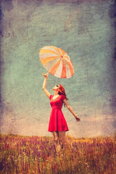 Femme en robe rouge avec parapluie sur prairie — Photo