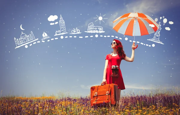 Woman in red dress with umbrella and suitcase — Stock Photo, Image