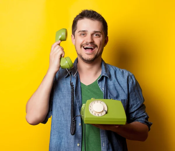 Парень в футболке с зеленым ретро-телефоном — стоковое фото