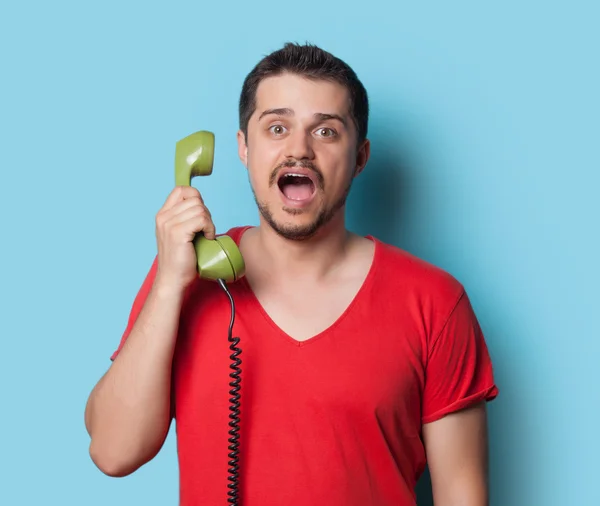 Guy in t-shirt with green retro phone — 스톡 사진