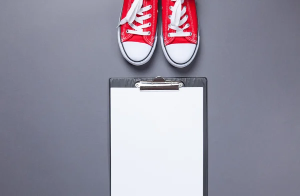 Clipboard with blank white paper and gumshoes — Stock Photo, Image