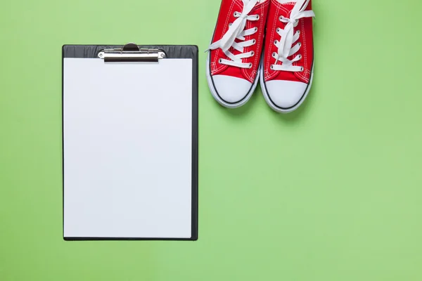 Clipboard and gumshoes on green background — Stock Photo, Image