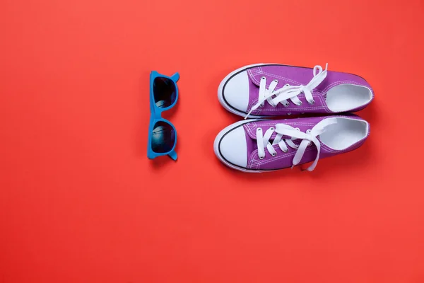 Sunglasses and gumshoes on red — Stock Photo, Image