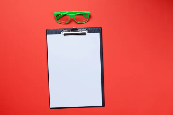 Prancheta com papel branco em branco e óculos de sol — Fotografia de Stock