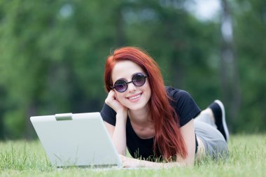 Redhaired Woman on meadow with laptop