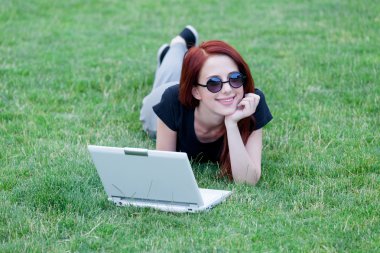 Redhaired Woman on meadow with laptop