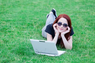 Redhaired Woman on meadow with laptop