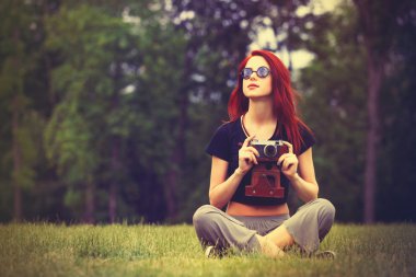 Redhaired Woman with camera sitting on grass