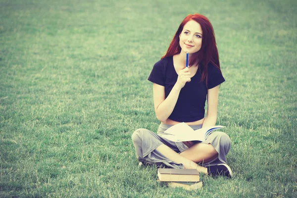 Redhaired Woman sitting studying on meadow — Stok fotoğraf