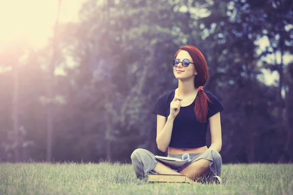 Redhaired Woman sitting studying on meadow — Stok fotoğraf