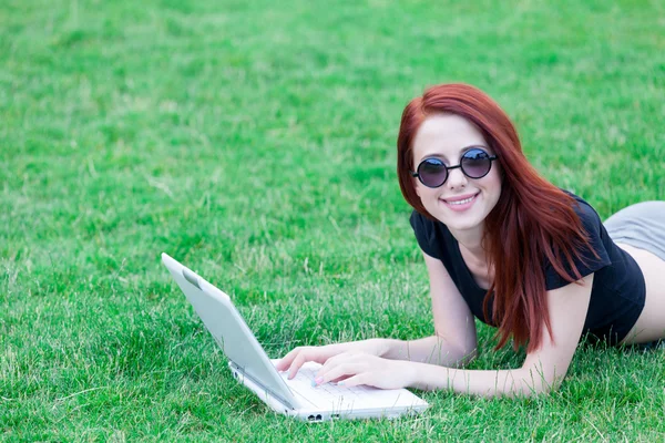 Donna dai capelli rossi sul prato con computer portatile — Foto Stock