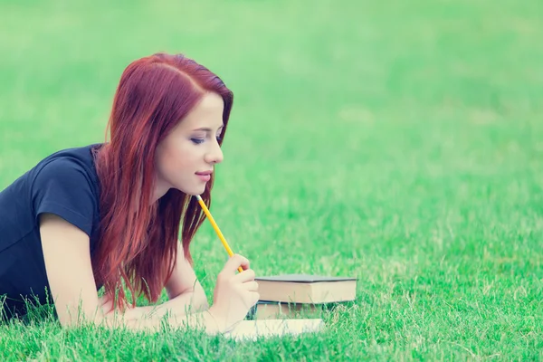 Redhaired Woman on grass with book and pencil — Φωτογραφία Αρχείου