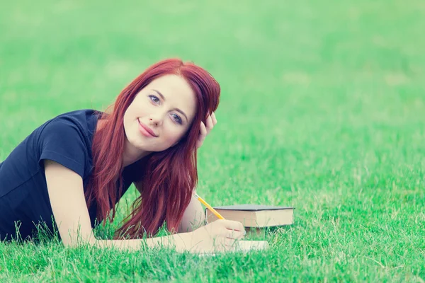 Redhaired Woman on grass with book — Stockfoto