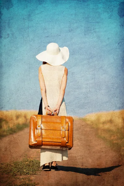 Rödhårig tjej med resväska på landsbygden road — Stockfoto