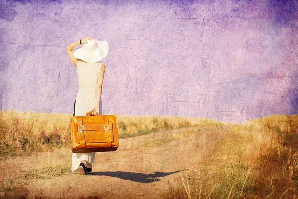 Руда дівчина з валізою на сільській дорозі — стокове фото