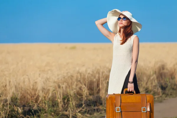 Redhead girl with suitcase at countryside road — Stock Photo, Image