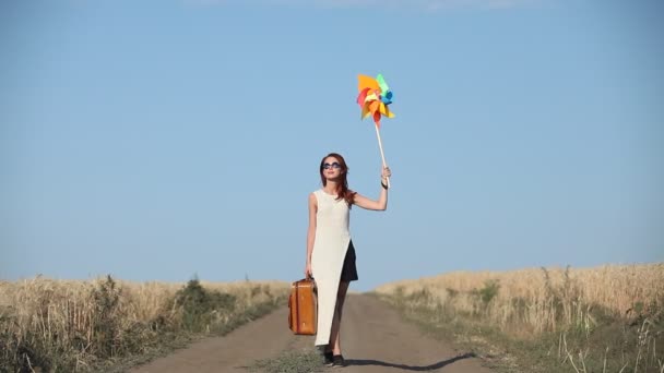 Chica con maleta y juguete de viento en el campo — Vídeos de Stock