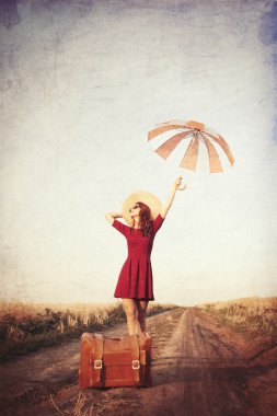 Bavul ve şemsiye ile Kızıl saçlı kız 