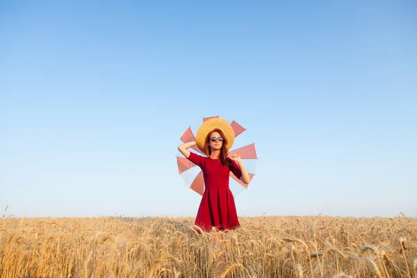 Девушка в красном платье с зонтиком и шляпой — стоковое фото