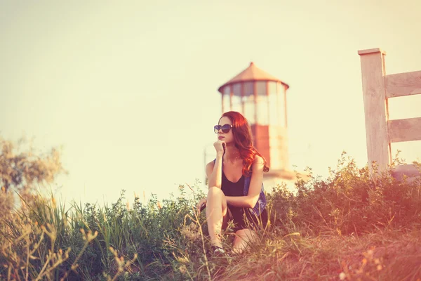 Ragazza seduta sull'erba vicino al faro — Foto Stock