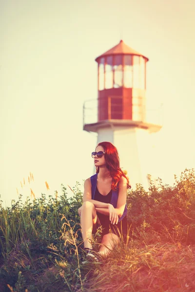 Lighthouse yakınındaki çimlerde oturan kız — Stok fotoğraf
