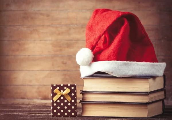 Santas hoed over boeken in de buurt van de doos van de gift — Stockfoto