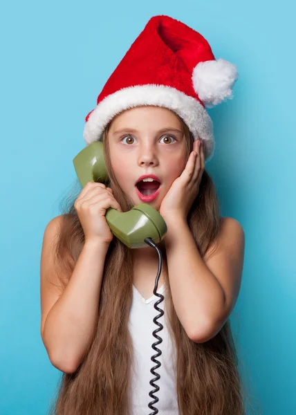 Girl in Santas hat calling by phone — Stock Photo, Image