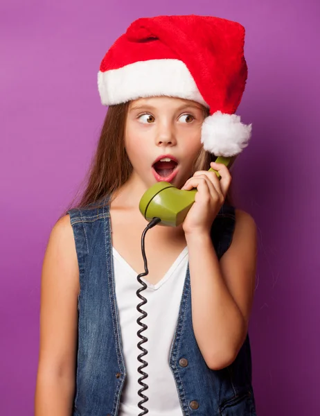 Girl in red Santas hat with green handset — Stock Photo, Image
