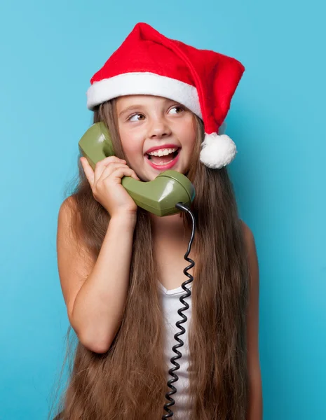 Girl in Santas hat calling by phone — Stock Photo, Image