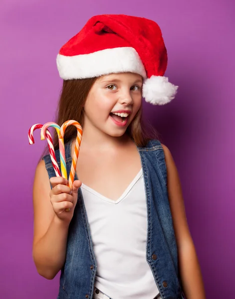 Girl in red Santas hat with candy — Stock Photo, Image
