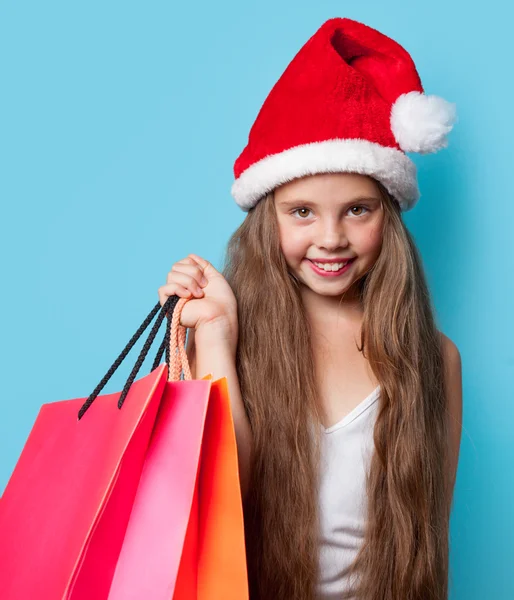 Girl in Santas hat with shopping bags — Stock Photo, Image