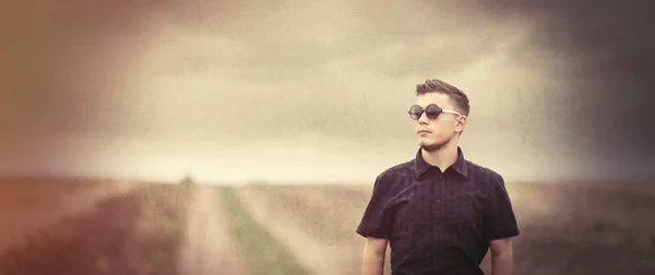 Jeune homme en lunettes de soleil à la campagne en plein air . — Photo