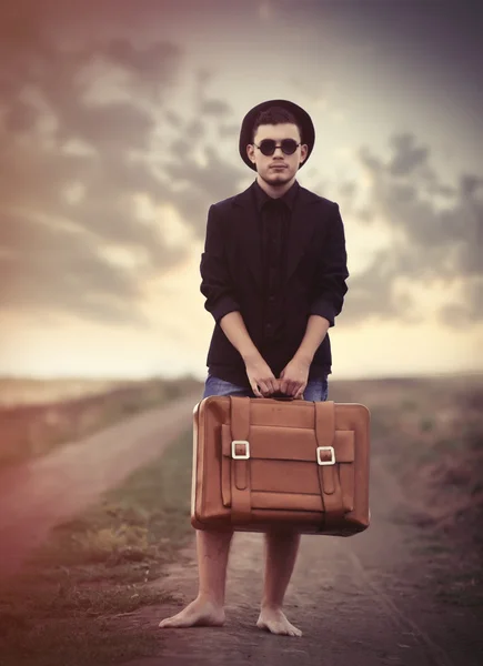 Стильный молодой человек с чемоданом — стоковое фото