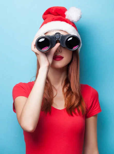 Frau mit Weihnachtsmütze mit Fernglas — Stockfoto