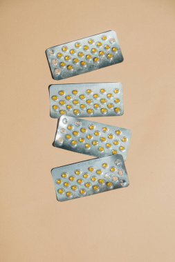 Şişkinlikleri tedavi etmek için kapsül içeren kabarcık paketleri bej bir arkaplan üzerinde düzenli olarak düzenlenir, minimalist bir sağlık hizmetleri kavramını somutlaştırır