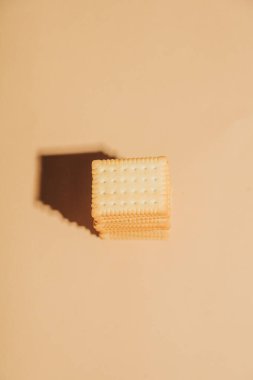 Yumuşak bej arkaplanlı, minimalist bir estetiğe sahip kremalı beyaz çay kurabiyeleri.