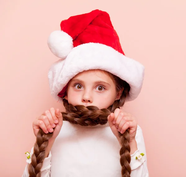 Девушка с косичками в шляпе Санта-Клауса — стоковое фото